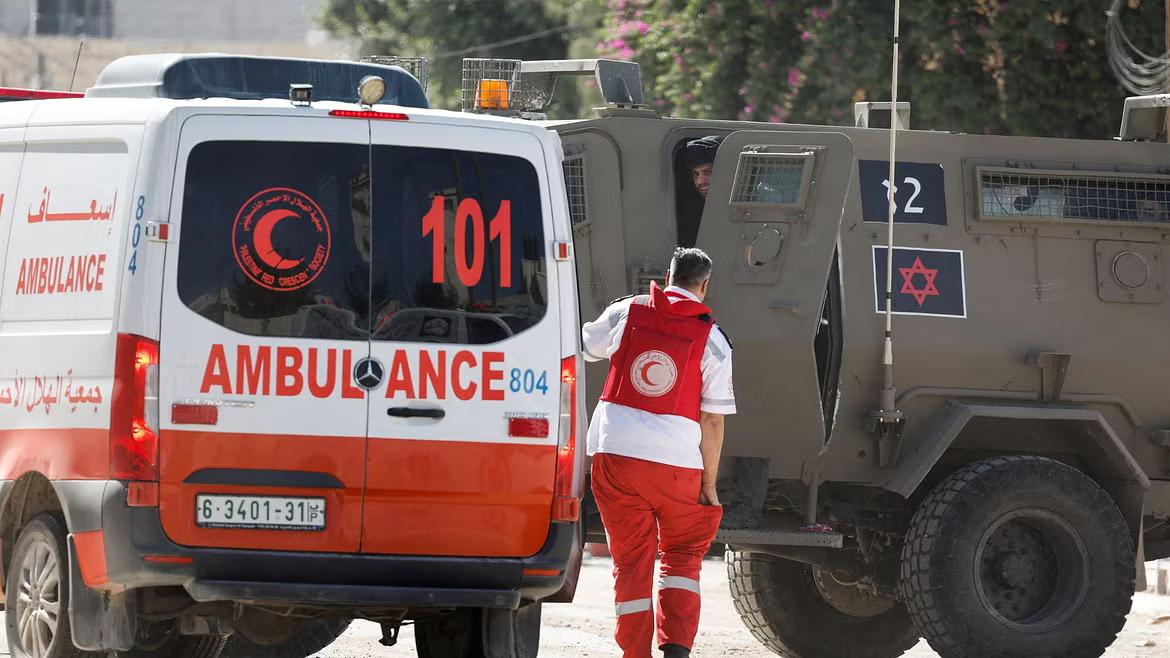 A member of the Palestine Red Crescent Society walks near an ambulance and Israeli military vehicle