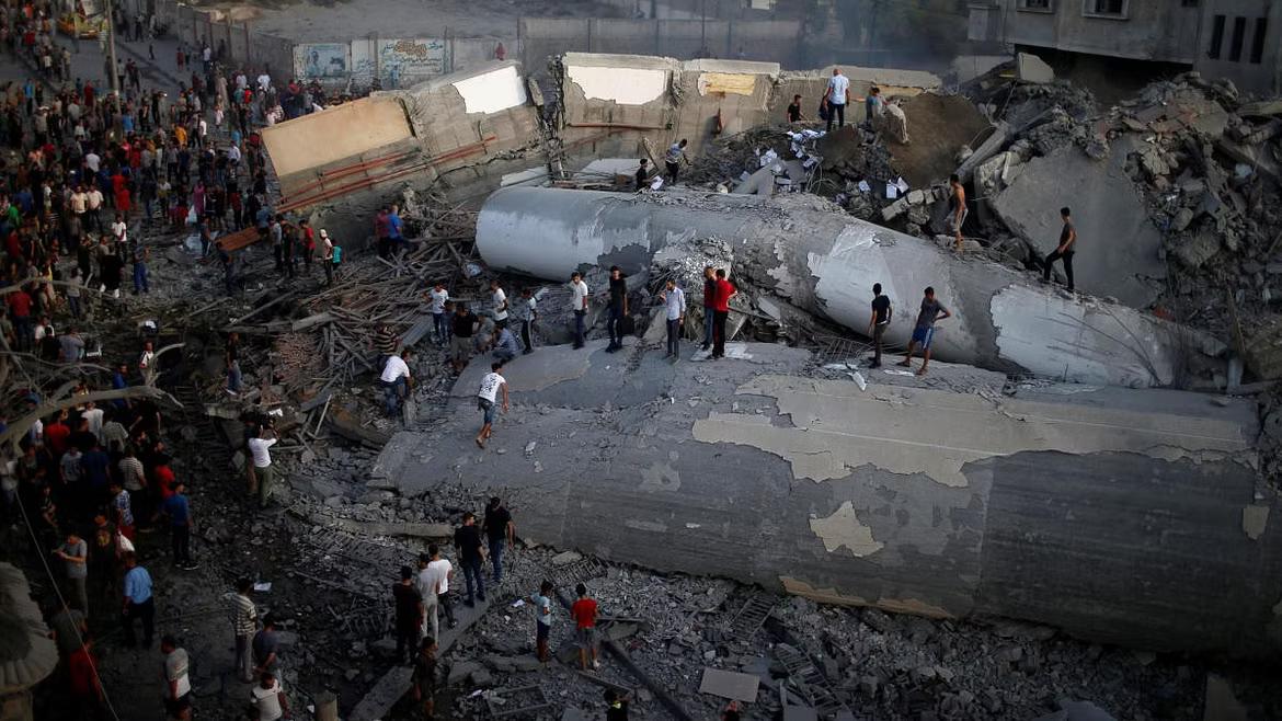 Palestinians gather around a building after it was bombed by Israel