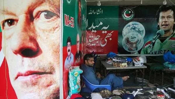 A vendor sits next to images of cricket star-turned-politician Imran Khan