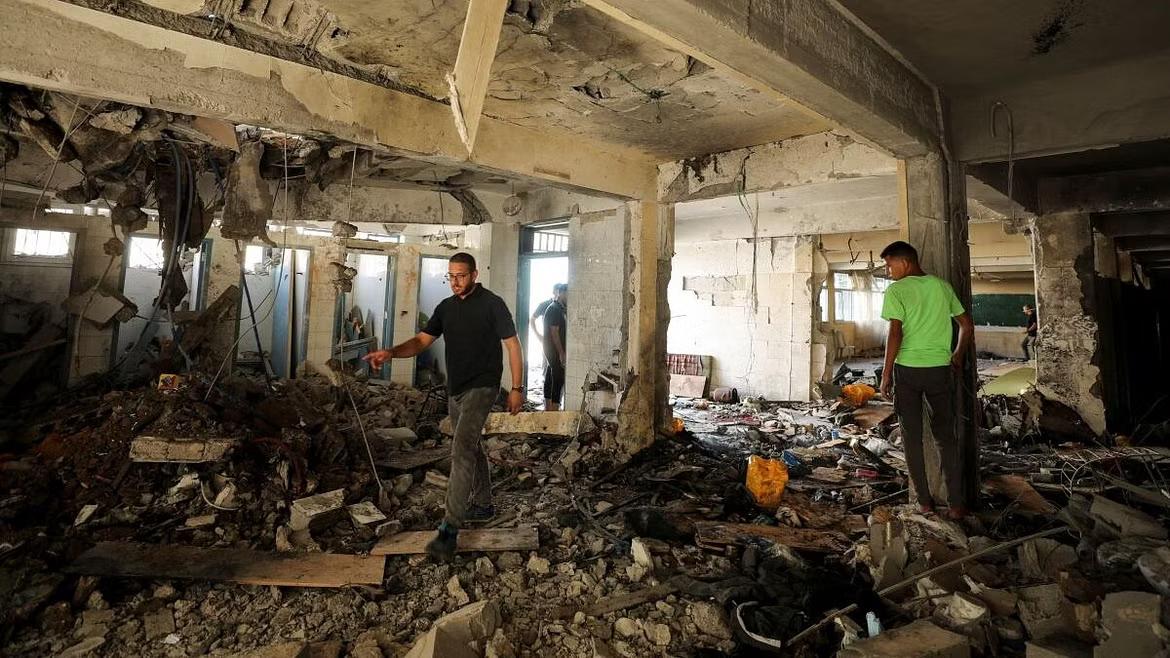 Palestinians inspect a school after it was hit by an Israeli strike