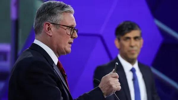 Keir Starmer seen in the foreground as Rishi Sunak looks on in the background