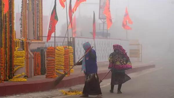 Sweepers clean a road amid dense morning fog before PM's arrival in Ayodhya on December 30.